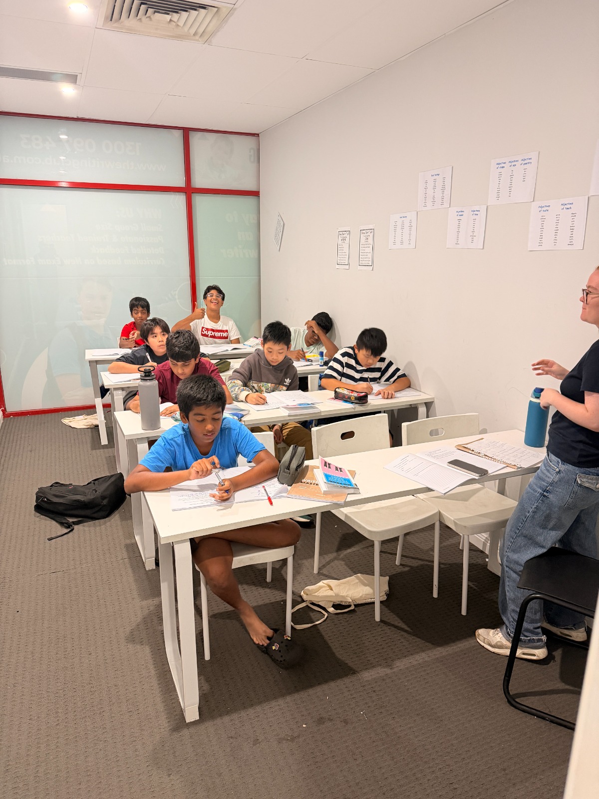 A focused young student writing in a busy classroom